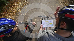 Mountain biking couple looking at map in the forest on a sunny day 4k. Top view