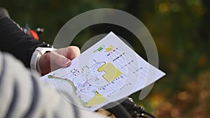 Mountain biking couple looking at map in the forest on a sunny day. close up