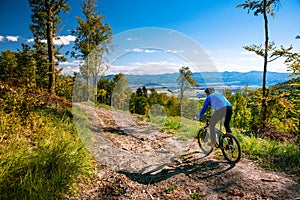 Mountain biking man riding downhill on bike at autumn mountains forest landscape. Outdoor sport activity. Colorful nature