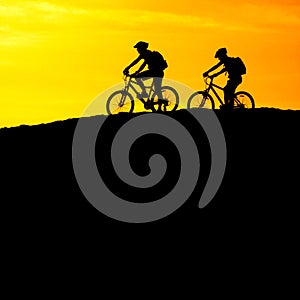 Mountain Biking Riders Silhouetted on Ridge with Mountains