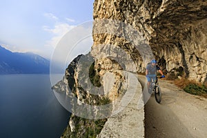 Mountain biking at sunrise man over Lake Garda on path Sentiero