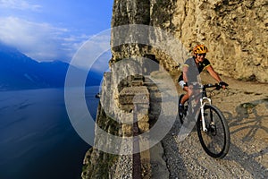 Mountain biking at sunrise woman over Lake Garda on path Sentier