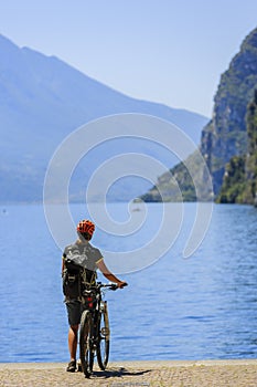 Mountain biking at sunrise woman over Lake Garda on path Sentier