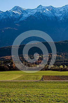 Mountain biking trough alpine landscape during autumn with snow topped mountains in Wildermieming, Tirol, Austria