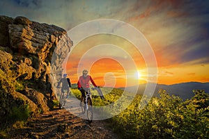 Mountain biking women and man riding on bikes at sunset mountain photo