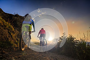 Mountain biking women and man riding on bikes at sunset mountain