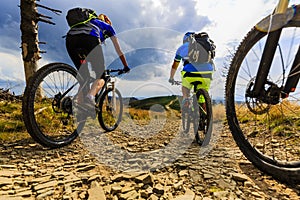 Mountain biking women and man riding on bikes at sunset mountain