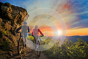 Mountain biking women and man riding on bikes at sunset mountain photo