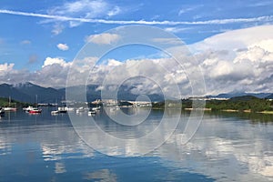 Mountain, blue sky, boats, yacht and sailboats on lake