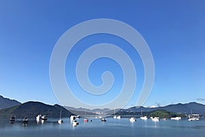 Mountain, blue sky, boats, yacht and sailboats on lake