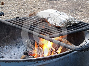 Mountain Camp Fire Cooking Foil Dinners on Grate Over Hot Pit