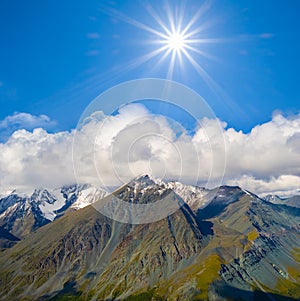 mountain chain in dense clouds under sparkle sun