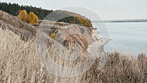 Mountain cliff and river in cloudy weather - dry grass in the front