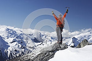Mountain Climber With Arms Raised On Snowy Peak