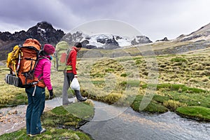 Mountain climber couple prepare to cross a small mountain stream in the Andes in Peru