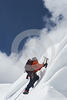 Mountain Climber Going Up Snowy Slope With Axes