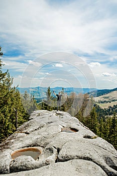 A mountain climber is high in the mountains against the sky, celebrating the victory, raising his hands up