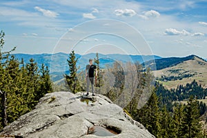 A mountain climber is high in the mountains against the sky, celebrating the victory, raising his hands up