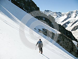 Mountain climber hiking down alone over a steep icy glacier in the Swiss Alps above Grindelwald