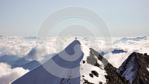 Mountain climber stands on an summit ridge with a great view behind