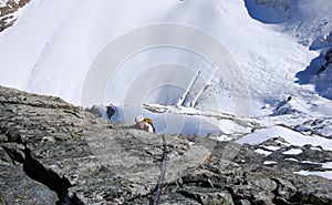 Mountain climber on a steep rocky climb far above a giant glacier