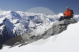 Mountain Climber Using Laptop On Mountain Peak