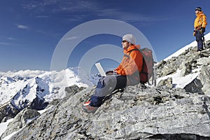 Mountain Climber Using Laptop On Mountain Peak