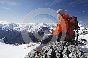 Mountain Climber Using Laptop On Mountain Peak