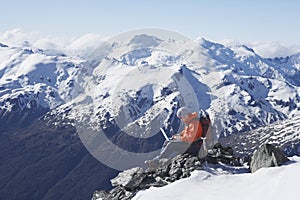 Mountain Climber Using Laptop On Mountain Peak