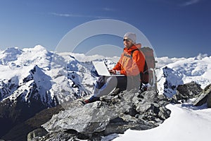 Mountain Climber Using Laptop On Mountain Peak