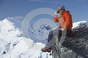 Mountain Climber Using Walkie Talkie Against Mountain Peak