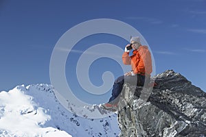 Mountain climber using walkie-talkie on mountain peak