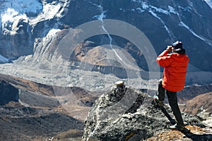 Mountain Climber in warm Jacket taking Picture of Valley