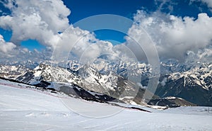 Mountain clouds over beautiful snow-capped peaks of mountains and glaciers. View at the snowy mountains