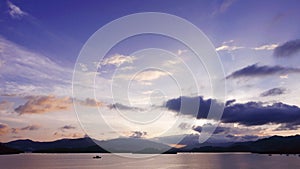 Mountain, cloudscape sky, boat on sea at sunset