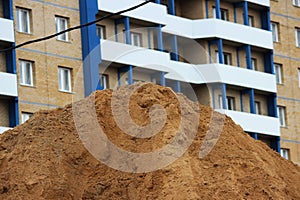 mountain of construction sand in the background of a brick house under construction with blue inserts and no glazed