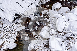 mountain creek streaming trough rocks covered in snow, winter landscape, aerial photography