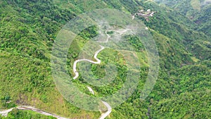 Mountain curve road passing along the slopes of mountains and hills covered with green forest and vegetation. Philippines, Luzon.