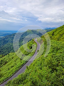 Mountain curvy tarmac road with hill range background and dramatic sky at morning