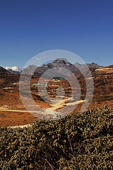 mountain dirt road going through the alpine valley and remote countryside area of tawang, surrounded by snowcapped mountains