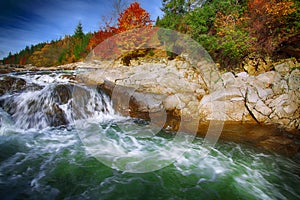 Mountain fast flowing river stream of water in the rocks at autumn