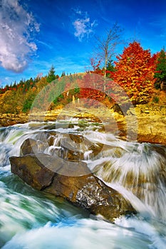 Mountain fast flowing river stream of water in the rocks at autumn