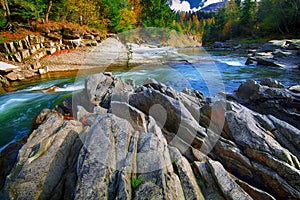 Mountain fast flowing river stream of water in the rocks at autumn