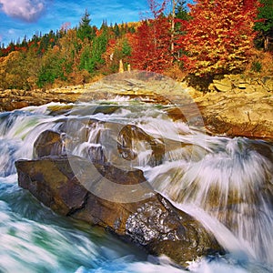 Mountain fast flowing river stream of water in the rocks at autumn