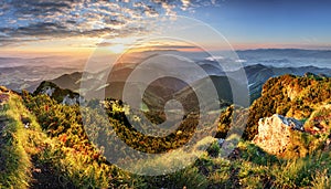 Mountain forest landscape under evening sky with clouds in sunlight.