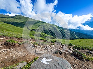 Mountain with green grass and blue sky partly cloudy.
