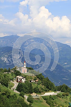 Mountain landscape with a small red church in Guardia, Trentino, Italy photo