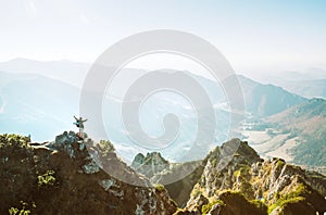Mountain hiker with backpack tiny figurine stands on mountain peak with beautiful panorama