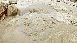 Mountain impetuous stream of brown water in rapid river Ganges close up