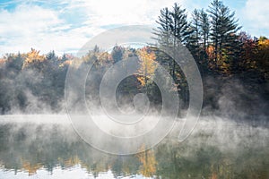 Misty lake with forested shores in autumn